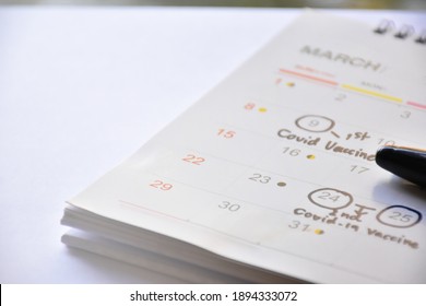 White Desk Calendar With Black English Words ‘1st And 2nd Covid-19 Vaccine’, Concept For Doctors’ Appointment Reminder To Get Coronavirus Vaccine. 