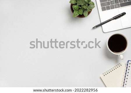 White desk  with Laptop, blank notepad, flower, coffee cup and pen. Flat lay top view copy space.