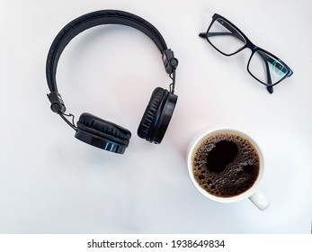 White Desk Table With Headphones, Coffee Cup And Glasses. Top View With Copy Space, Flat Lying Down.