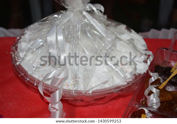 white dessert cake in plastic packaging on a red\
tablecloth table