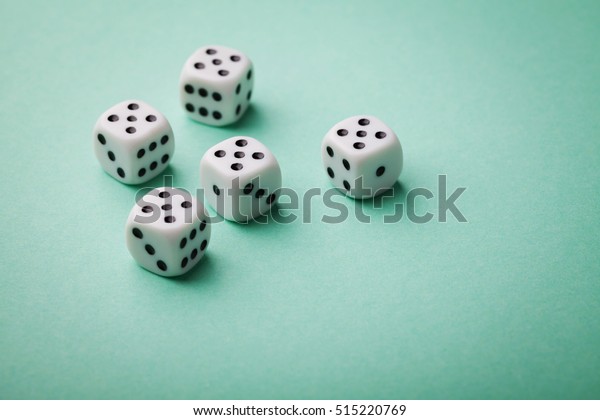 White dice on\
green background. Gambling devices. Copy space for text. All number\
five. Game of chance\
concept.