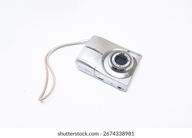 white digital compact camera seen from the front against a white background, photographed from a top angle.