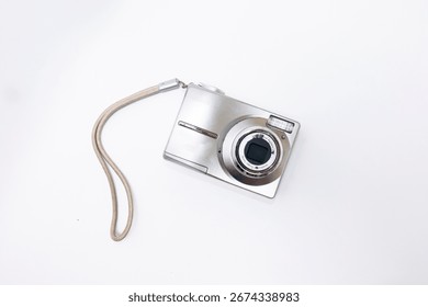 white digital compact camera seen from the front against a white background, photographed from a top angle