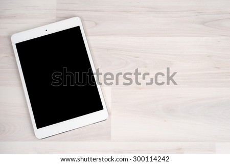 White digital tablet on bright wooden table