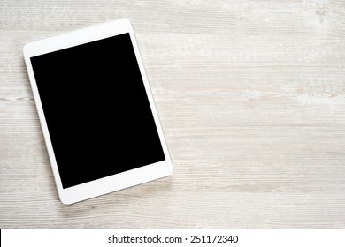 White digital tablet on wooden table - Shutterstock ID 251172340