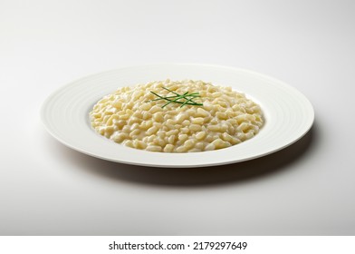 White dinner plate with parmesan cheese risotto and chives isolated on white background