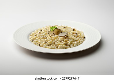 White dinner plate with risotto and slices of black truffle isolated on white background
