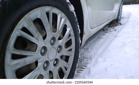 White Dirty Car wheel on snow road. Messy, salt, chemicals in winter. Tire. Ecology problem in city. Protection and wash vehicle concept. Driving. Auto hubcap. Travelling. Car industry.