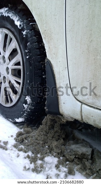 White dirty Car wheel on snow road. Messy,
salt, chemicals in winter. Tire. Ecology problem in city.
Protection and wash vehicle concept. Driving. 
