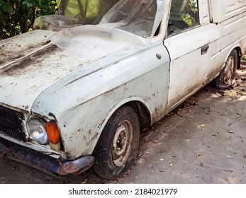 White dirty old auto with flat tires. Dirty white old model car with flat tires stands covered with polyethylene - Powered by Shutterstock