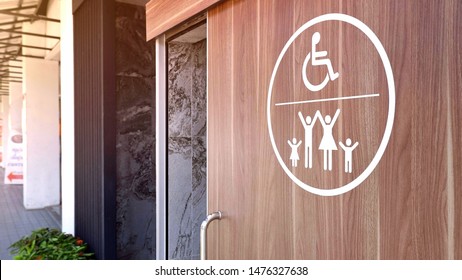 White Disabled Wheelchair And Family Restroom Sign On Wooden Sliding Bathroom Door With Blurred Background In Public Area