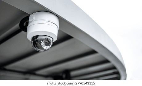 White dome CCTV security camera hanging on steel roof. Surveillance equipment for safety and protection. Security monitoring system technology