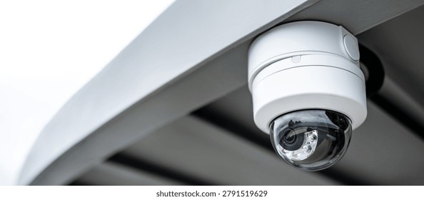 White dome CCTV security camera hanging on steel roof. Surveillance equipment for safety and protection. Security monitoring system technology