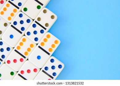 White Dominoes With Brightly Colored Dots On Blue Background Shot Overhead With Copy Space