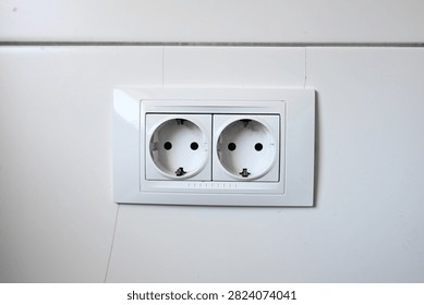 White double Schuko wall socket Type F power outlet. Double electric power socket on a white wall. Modern dual electrical outlet.