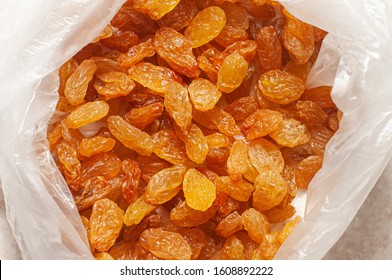 White dried raisins in a plastic bag on a white table. The rate of dried yellow grapes for an adult. Dried fruits