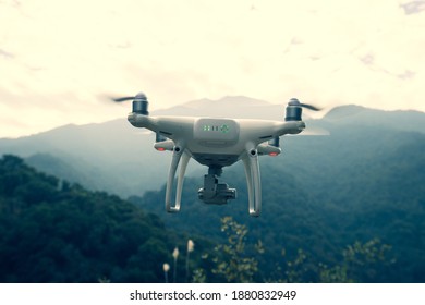 White drone with camera flying in spring mountains