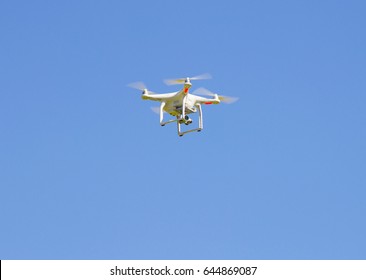 A white drone flying in blue sky.