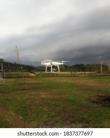 A white drone hovering over the grass field during the day. Great for technology, backgrounds and more.