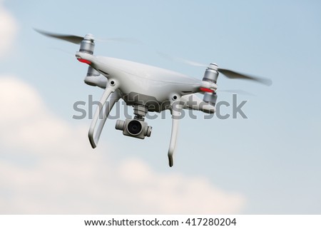 White drone, quadrocopter with photo camera flying in the blue sky. Concept,