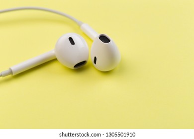 white earphones on yellow background - Shutterstock ID 1305501910