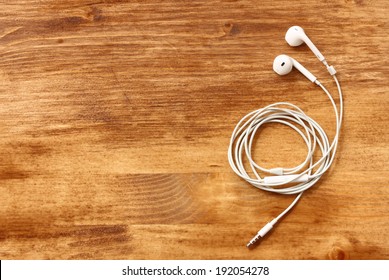 White Earphones Over Wooden Board