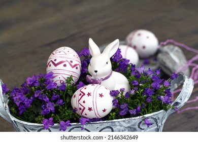 White Easter bunny with eggs sitting in flowers.