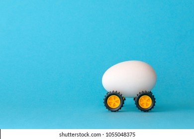 White Easter egg on wheels on a blue background