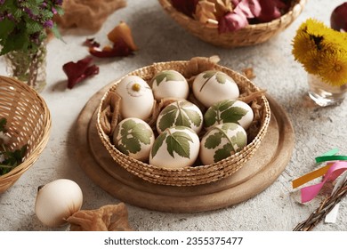White Easter eggs with fresh leaves attached to them - preparation for dyeing with onion peels