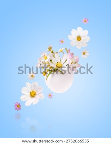 White Easter eggs with spring pear, cosmea and strawberry flowers on blue background. Happy Easter.