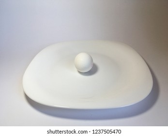 White egg on a white plate on a white background. The birth of life. Chicken egg.
