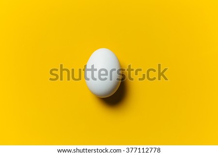 White egg on the yellow background in center. Design, visual art, minimalism