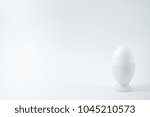 White egg standing on egg cup isolated on white background, copy space. Boiled egg in stand. Healthy food concept, minimalism