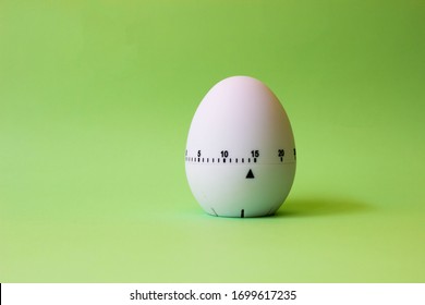 White Egg Timer On Green Background. Happy Easter In The Kitchen. Home Related, Home Staying. Free Copy Space. Flat Lay, Top View