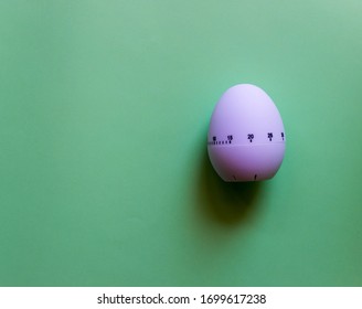 White Egg Timer On Green Background. Happy Easter In The Kitchen. Home Related, Home Staying. Free Copy Space. Flat Lay, Top View