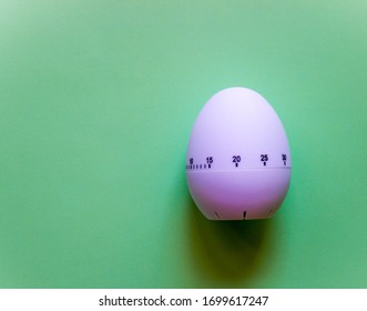 White Egg Timer On Green Background. Happy Easter In The Kitchen. Home Related, Home Staying. Free Copy Space. Flat Lay, Top View