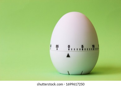 White Egg Timer On Green Background. Happy Easter In The Kitchen. Home Related, Home Staying. Free Copy Space. Flat Lay, Top View