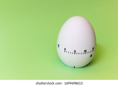 White Egg Timer On Green Background. Happy Easter In The Kitchen. Home Related, Home Staying. Free Copy Space. Flat Lay, Top View