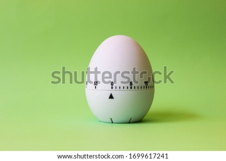 white egg timer on green background. Happy Easter in the kitchen. Home related, home staying. Free copy space. Flat lay, top view