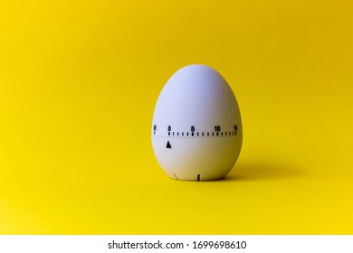 white egg timer on yellow background. Happy Easter in the kitchen. Home related, home staying. Free copy space. Flat lay, top view.