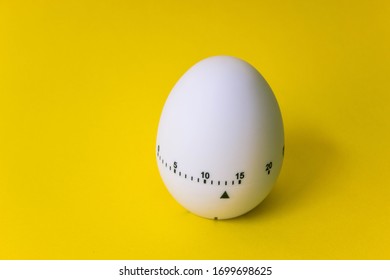 White Egg Timer On Yellow Background. Happy Easter In The Kitchen. Home Related, Home Staying. Free Copy Space. Flat Lay, Top View.