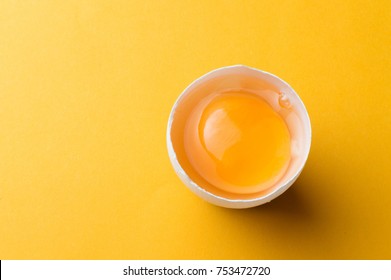 White egg and egg yolk on the yellow background.