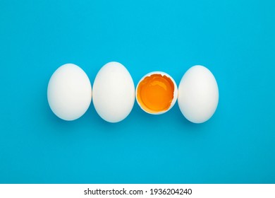 White eggs and egg yolk on the blue background. Easter concept. Top view.