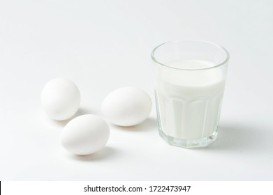 White Eggs And Milk In A Glass Cup On A White Background