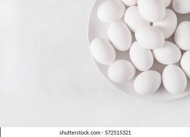 White eggs on a white plate on a white background. 