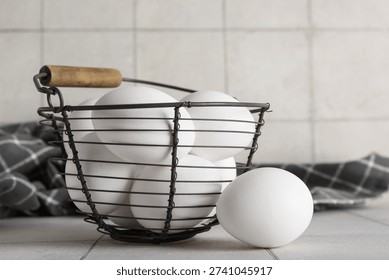 White eggs in rustic wire basket on kitchen counter with tiled background and copy space