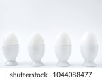 White eggs standing on egg cup isolated on white background, copy space. Row of boiled eggs in stand. Healthy food concept 