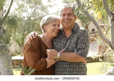 White elderly couple hug each other tenderly inside a park