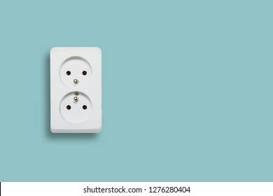 White electric socket on blue pastel background. The concept of electric power consumption, use of electricity. Savings on energy supply, power supply of various household items. Minimalist photo.