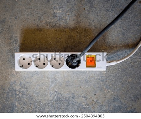A white electric splitter Power socket with plug from device. background is a concrete floor. construction and renovation, copy space and flat lay